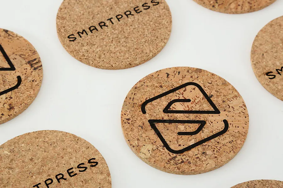 Promotional coasters lined up in rows with cork material and the Smartpress name and logo in black.