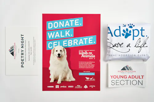 A red poster printed with a white dog and Donate. Walk. Celebrate. next to a folded table throw and library sign.