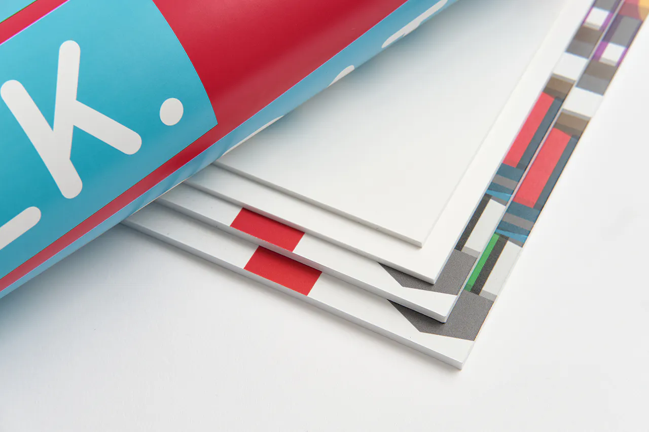 Four foam signs fanned out on top of each other with red, green and gray graphics and a rolled-up poster on top of them.