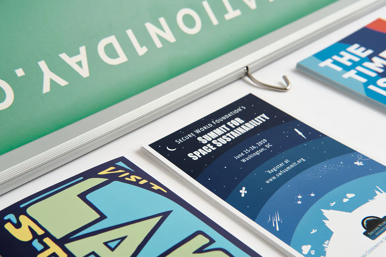 A stack of brochures printed with Summit for Space Sustainability next to decals printed with Lake Street.