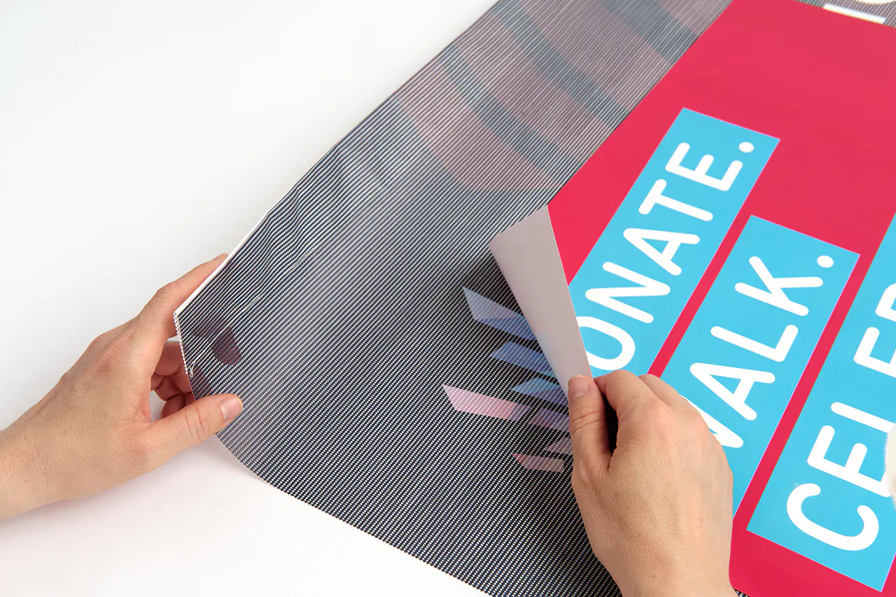 Two hands rolling back the corners of a banner and a poster printed with a red background and Donate in blue and white.