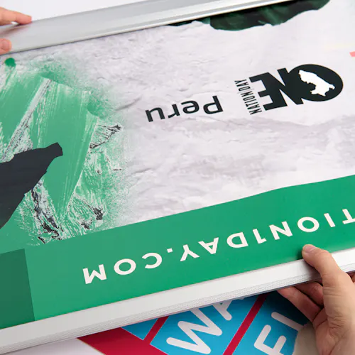 Two hands unrolling a custom retractable banner printed with One Nation Day Peru in green, white and black.