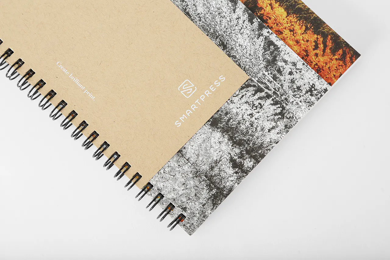 A wire bound booklet printed with Smartpress in white ink on Kraft paper on top of a cover printed with trees.