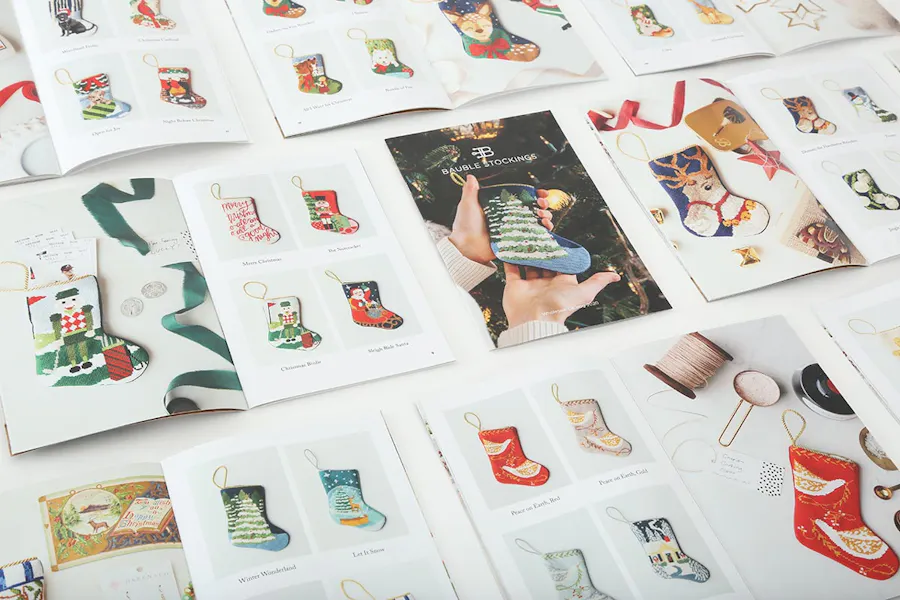 Holiday catalogs laying open in three rows with images of custom made stockings and product names.