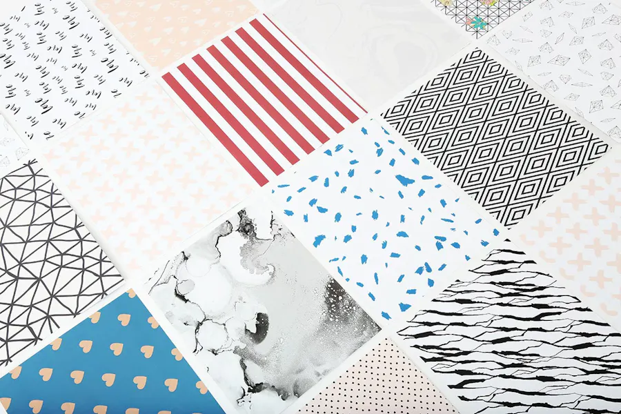 Sheets of scrapbooking paper laid out in rows with custom artwork and various patterns.