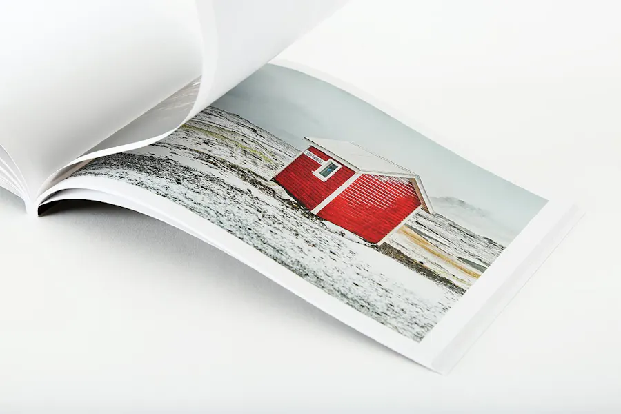 A photography portfolio laying open to an image of a red shed in a snowy field.