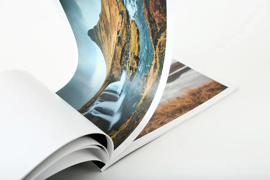 A photography booklet laying open with pages flipping through images of landscapes.