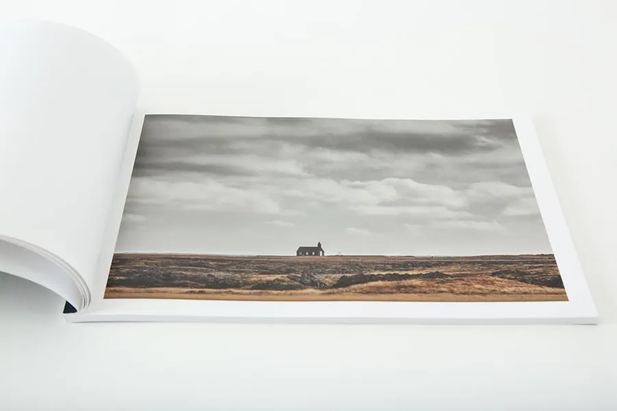A photography lookbook laying open to an image of a barren field and a church in the distance.