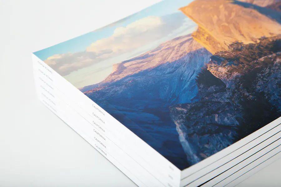 A stack of photography portfolios printed with a perfect binding and a landscape image on the cover.
