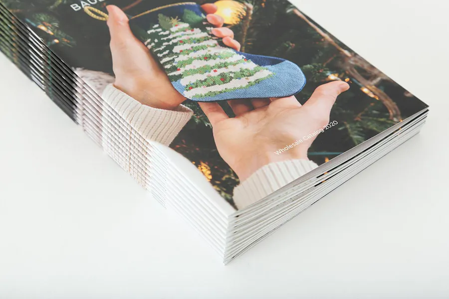 A stack of custom holiday catalogs printed with two hands holding a stocking on the cover.