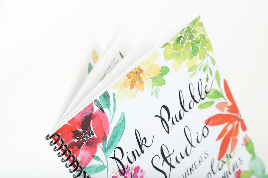 A watercolor guide book printed with a spiral binding and flowers and Pink Puddle Studio on the front.