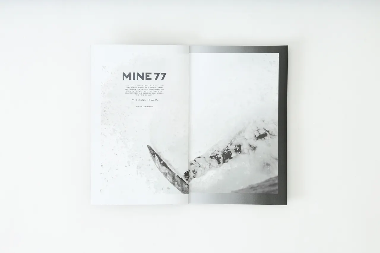 A Mine77 lookbook laying open to a black and white image of a person snowboarding.