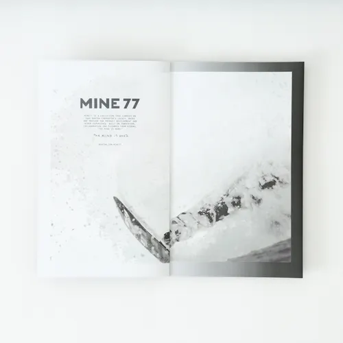 A Mine77 lookbook laying open to a black and white image of a person snowboarding.
