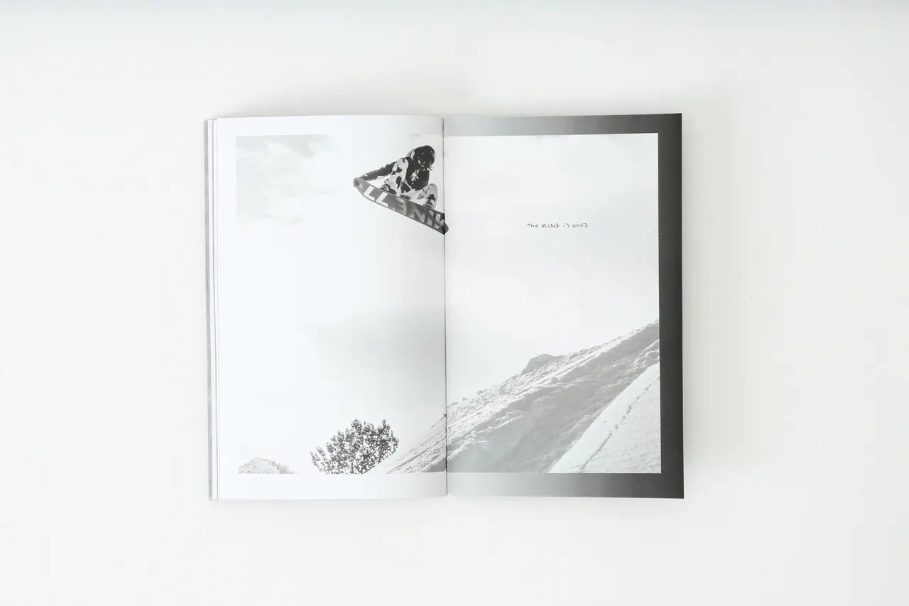 A Mine77 lookbook laying open to images of a person snowboarding.