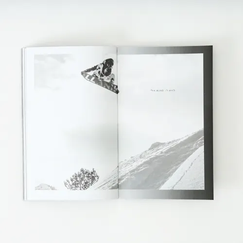 A Mine77 lookbook laying open to images of a person snowboarding.