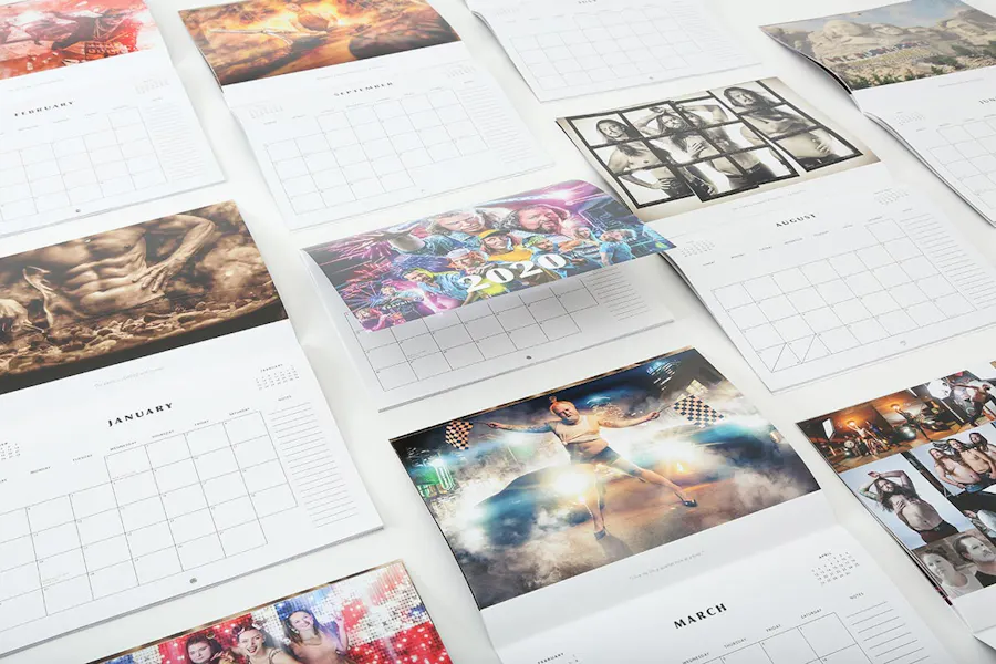Wall calendars laying open in four rows with custom imagery.