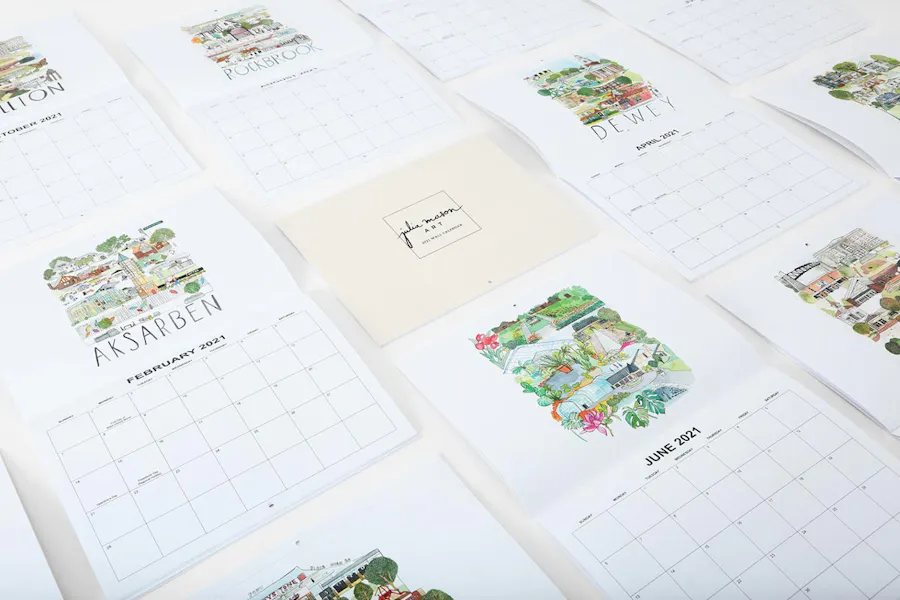 Custom calendars with saddle stitch bindings laying open with illustrations of neighborhoods in Omaha, Nebraska.