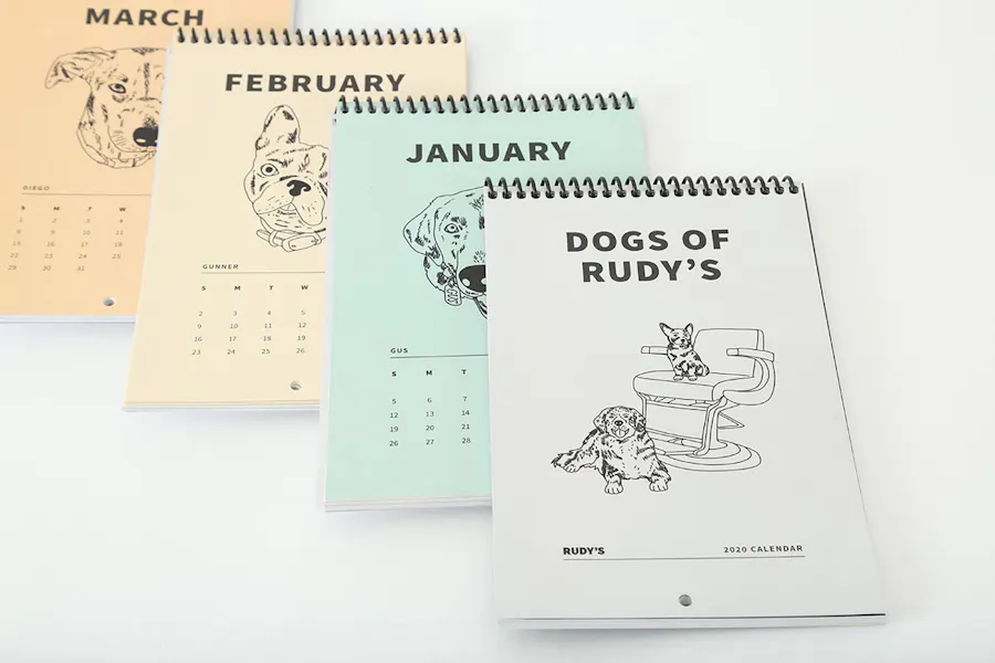 Four tiered custom calendars with spiral bindings and illustrations of dogs.
