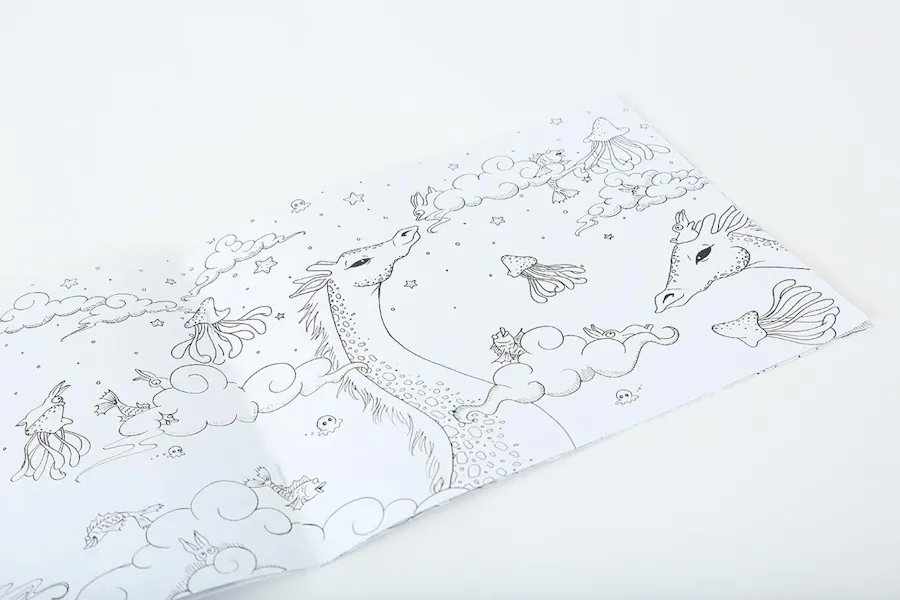 A custom coloring book laying open to a scene with fish, jellyfish, stars, clouds and dragons.