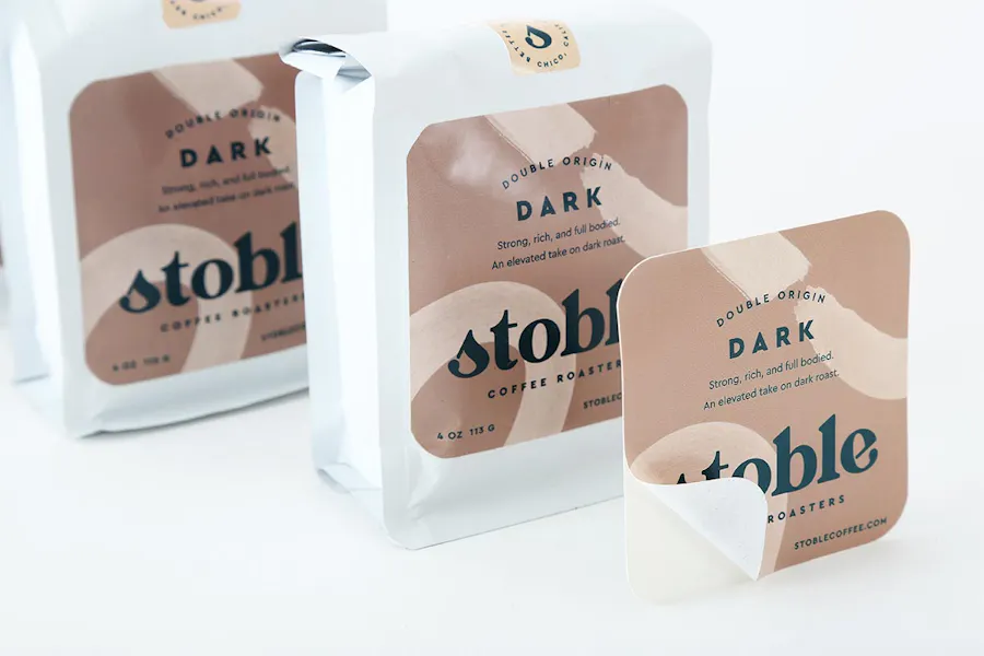 Bags of coffee beans with custom product labels on them printed with Double Origin Dark and stoble in black text.