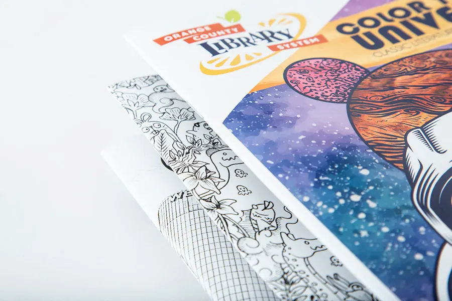 A stack of three custom coloring books with saddle stitch bindings.