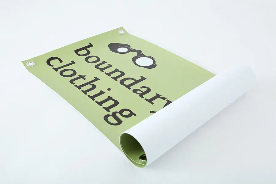 A marketing banner rolled up on one side with boundary clothing in black text on a green background.