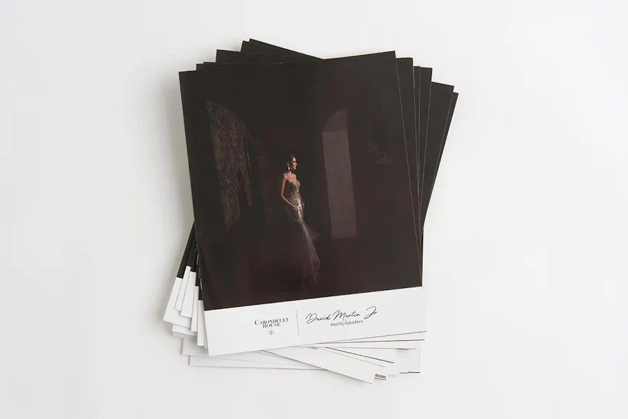 A stack of custom booklets printed with bridal photography and a woman in a strapless gown on the cover.