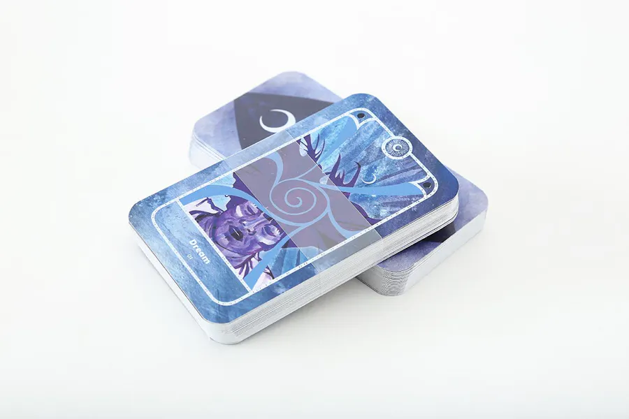 Two tarot card decks stacked on top of each other with a blue and purple design and clear belly bands.