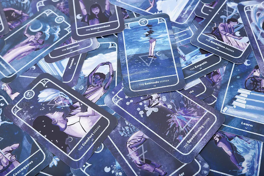 Custom oracle cards scattered in a pile with a blue and purple design.