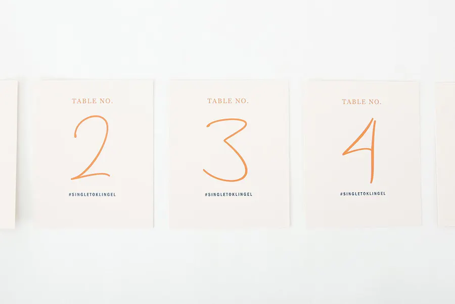 Three collated table number cards lined up in a row and printed with Table No. 2, Table No. 3. and Table No. 4 in orange.