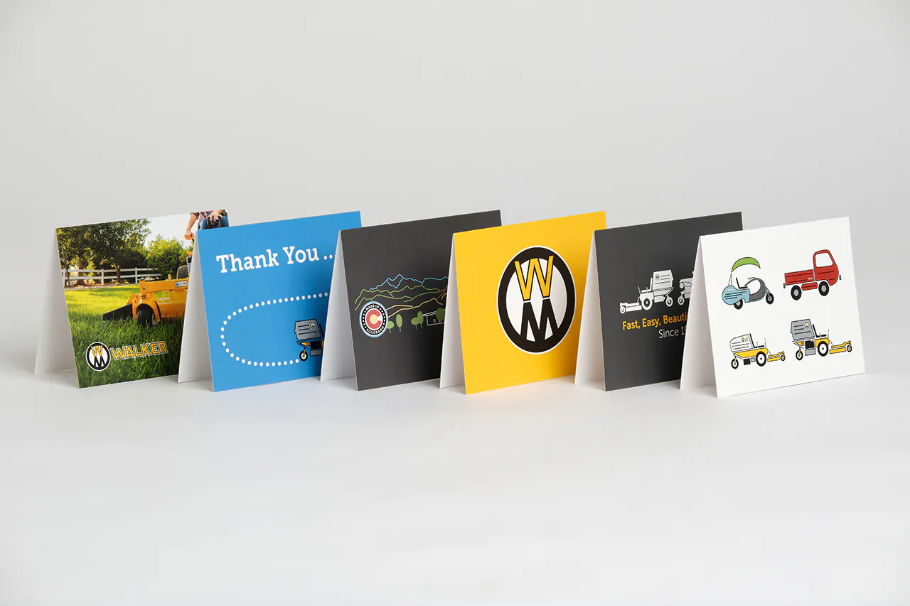 Walker Mower greeting cards with various designs in black, yellow and blue standing in a line.