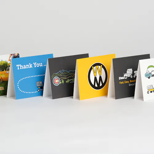 Walker Mower greeting cards with various designs in black, yellow and blue standing in a line.