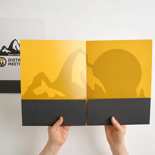 Two hands holding open a pocket folder with a black and yellow design.