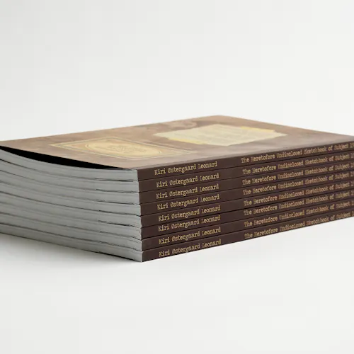 A stack of custom printed sketchbooks with Kiri Ostergaard Leonard and the title on each spine.