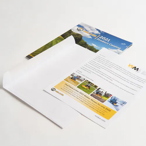 A Walker Mower product catalog and marketing flyer laying next to a plain white envelope.