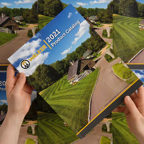Two hands holding a Walker Mower product catalog printed with a house and a large green lawn on the cover.