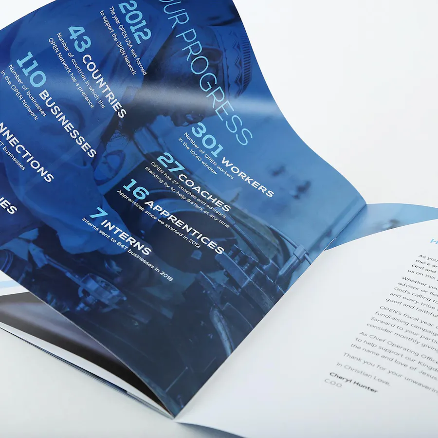 An annual report with a saddle stitch binding laying open to company stats.