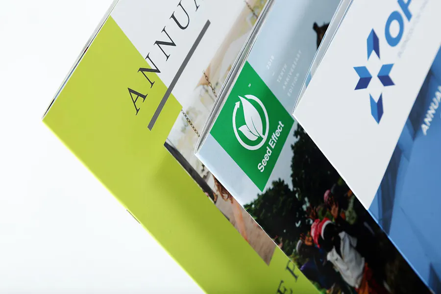 Three annual report booklets in a tiered stack with designs in green, white and blue.