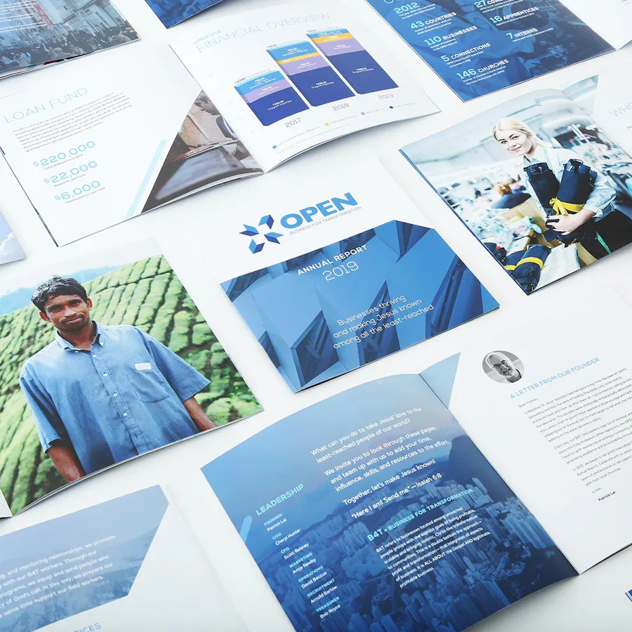 Annual report booklets laying open to statistics and images of employees and graphs.