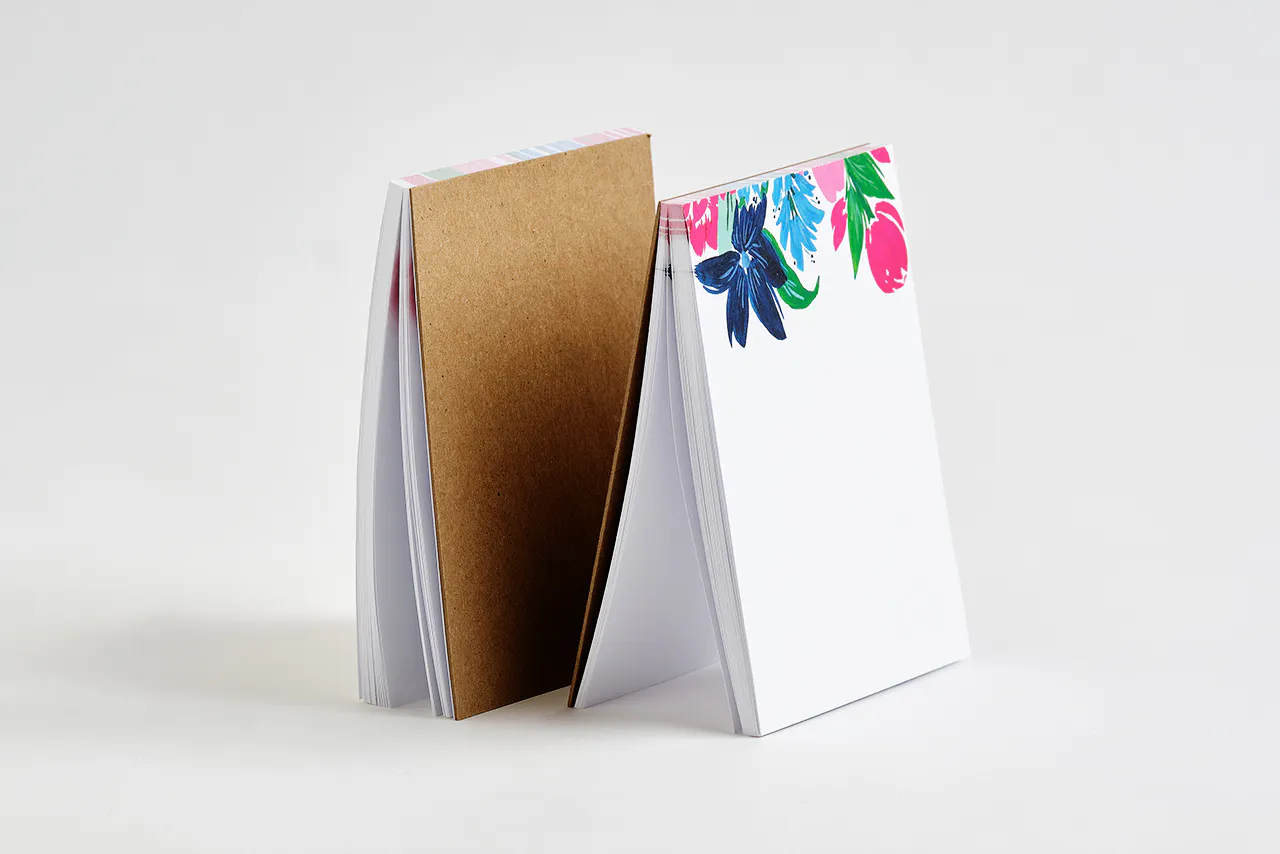 Two custom printed notepads with a bright floral design at the top.