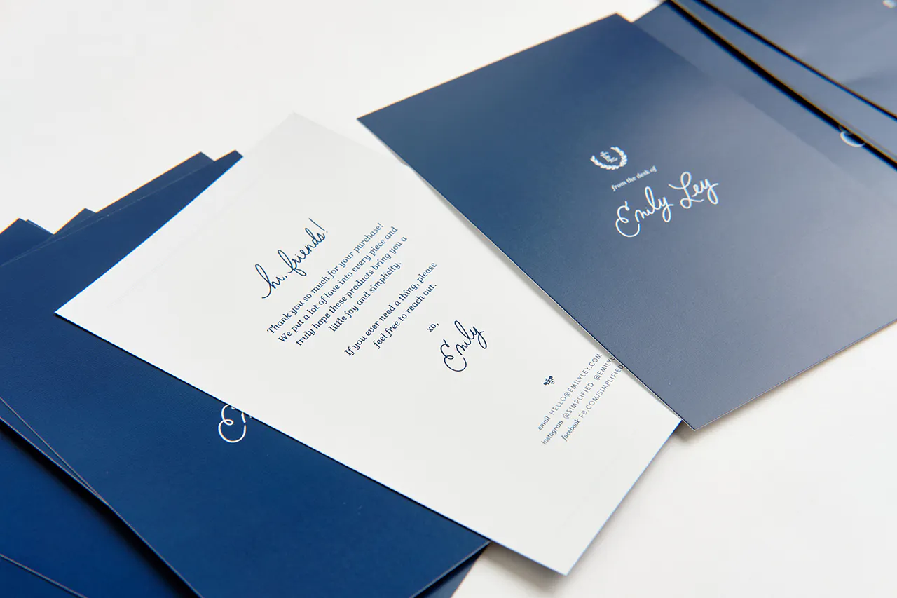 A stack of fanned-out package inserts printed with a navy blue design and a welcome note on the back.
