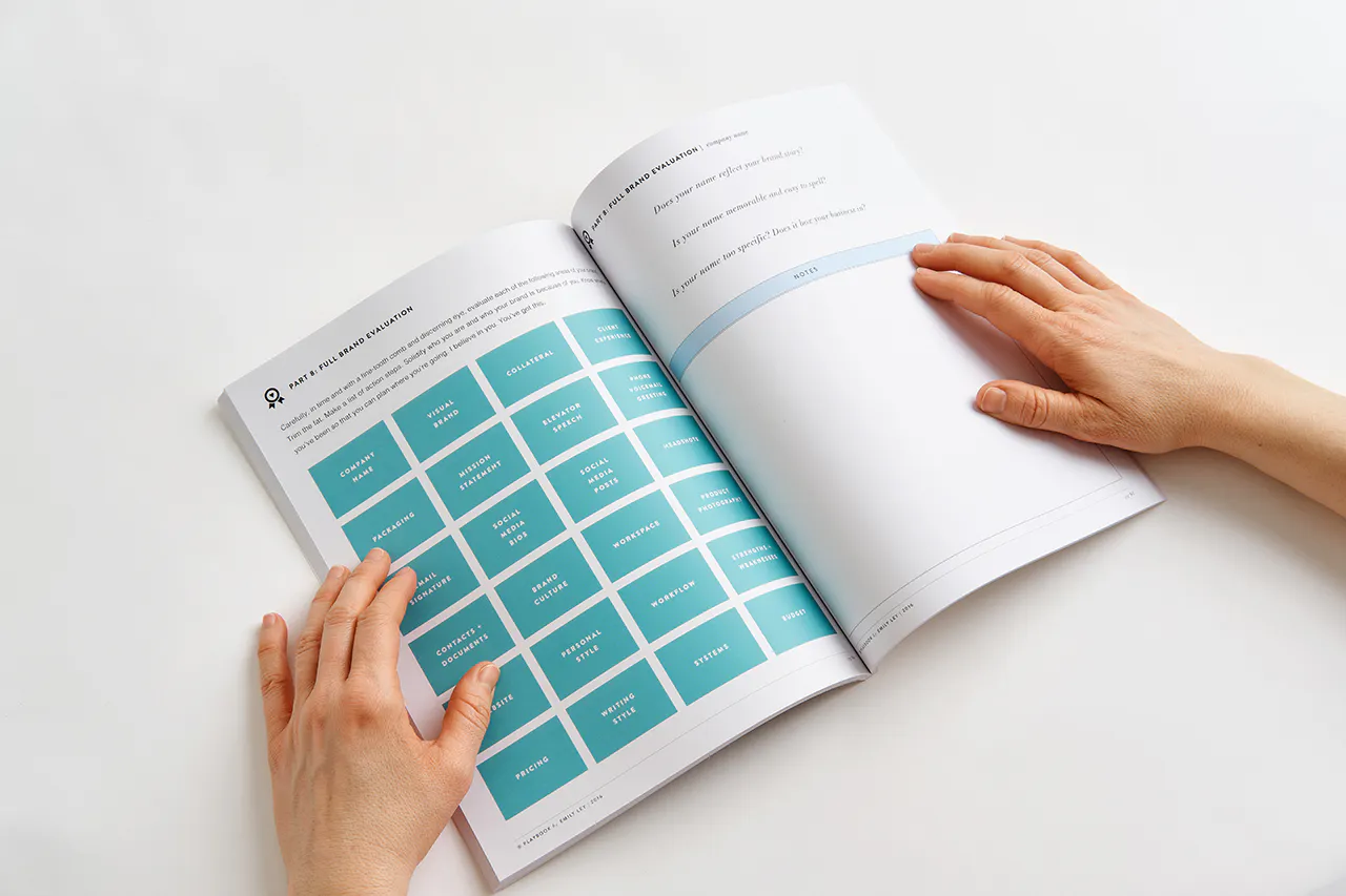 Two hands holding open a marketing workbook to information about evaluation your brand.