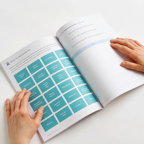 Two hands holding open a marketing workbook to information about evaluation your brand.