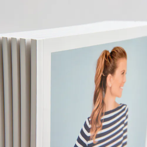 A stack of brand booklets standing with a woman in a striped top on the cover and a perfect binding.