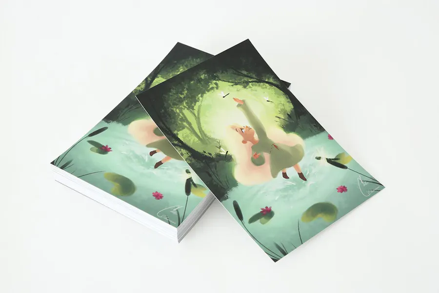 A stack of custom postcards printed with an illustration of a girl in a forest and Soft Touch laminate.