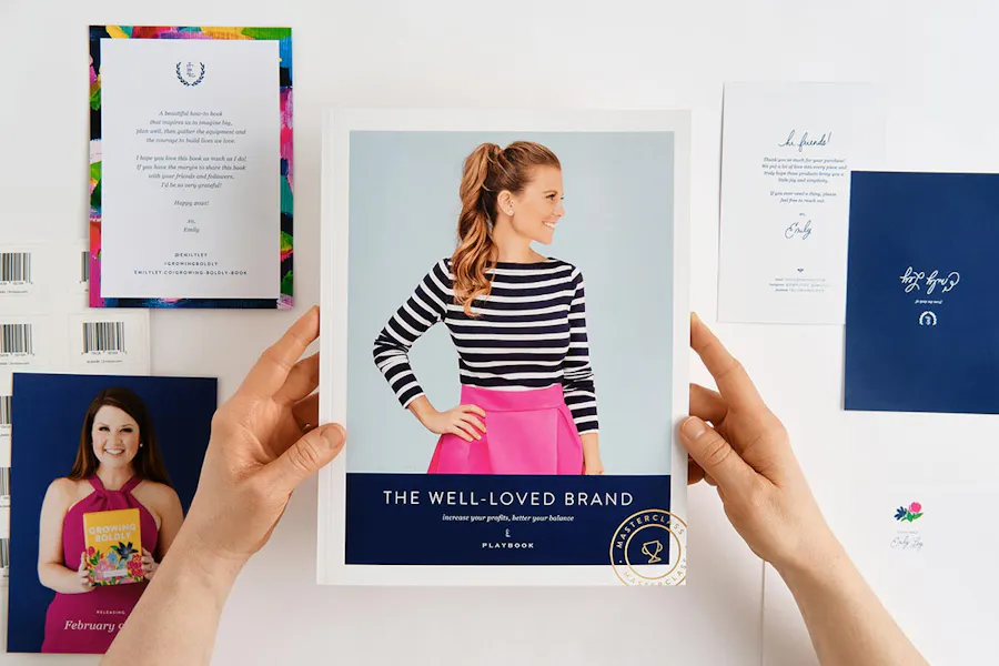 Two hands holding a branded booklet with other custom stationery surrounding it.