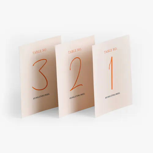 Three wedding table place cards printed with a peach background and a table number in bright orange on each one.
