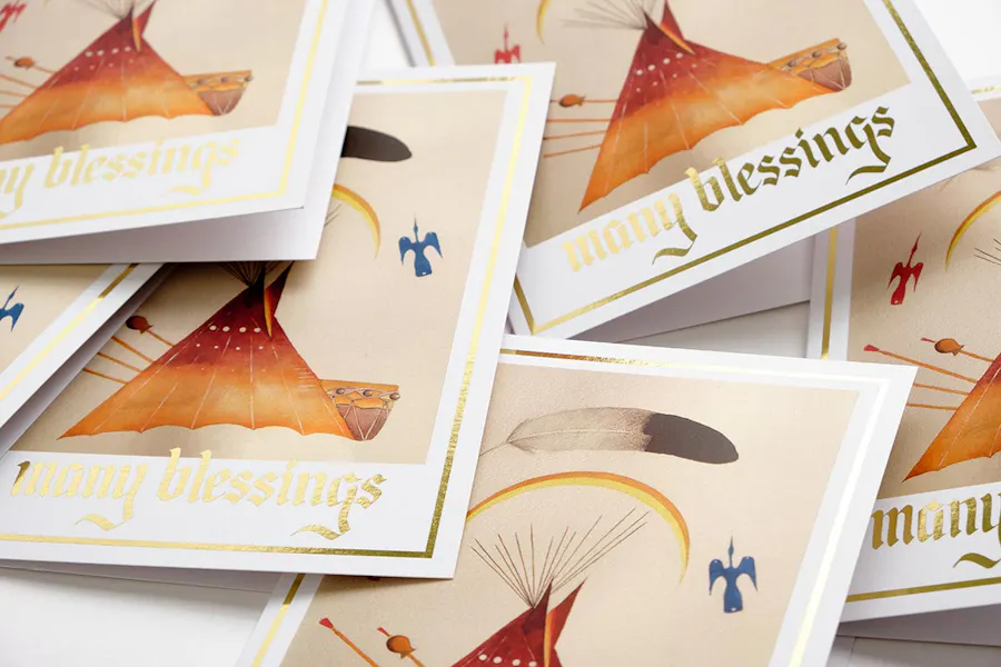 A stack of custom greeting cards printed with many blessings in gold foil on the front.