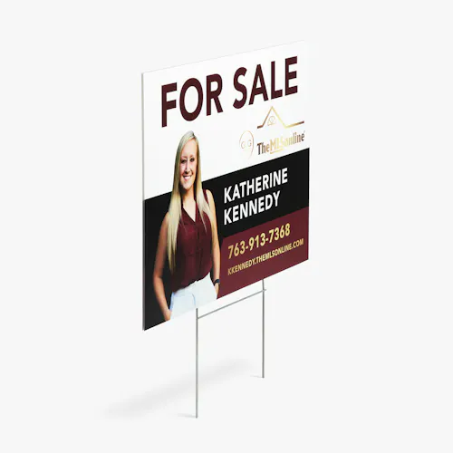 A yard sign printed with For Sale in dark red with an image of a smiling woman and Katherine Kennedy in white.