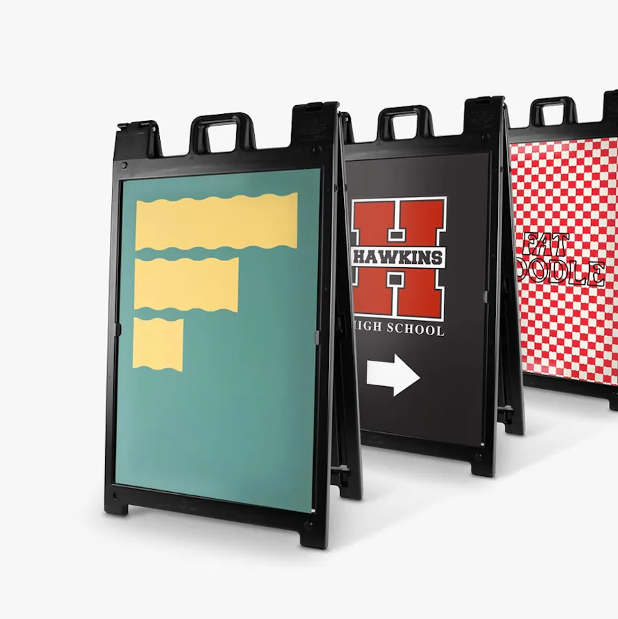 Three custom sidewalk signs with black frames and artwork in green and yellow, black and red and red and white.
